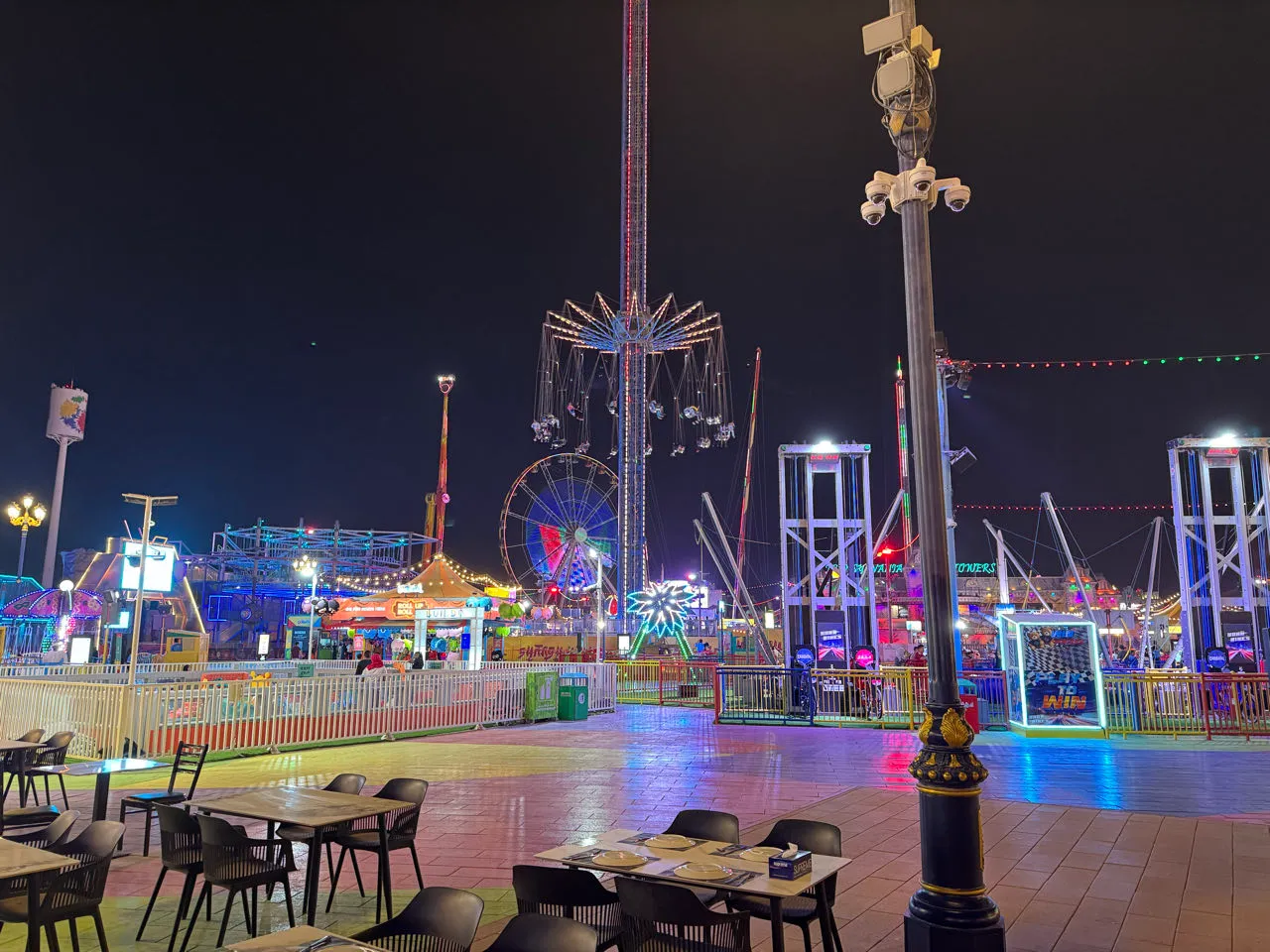 Bunt beleuchtete Fahrgeschäfte am Abend in Global Village