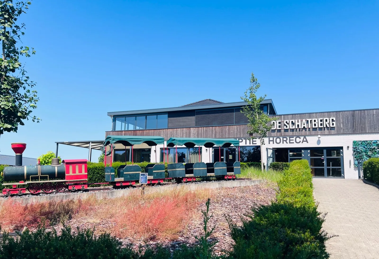 Hauptgebäude von De Schatberg mit Rezeption und Restaurant, davor die rot-grüne Bimmelbahn des Parks