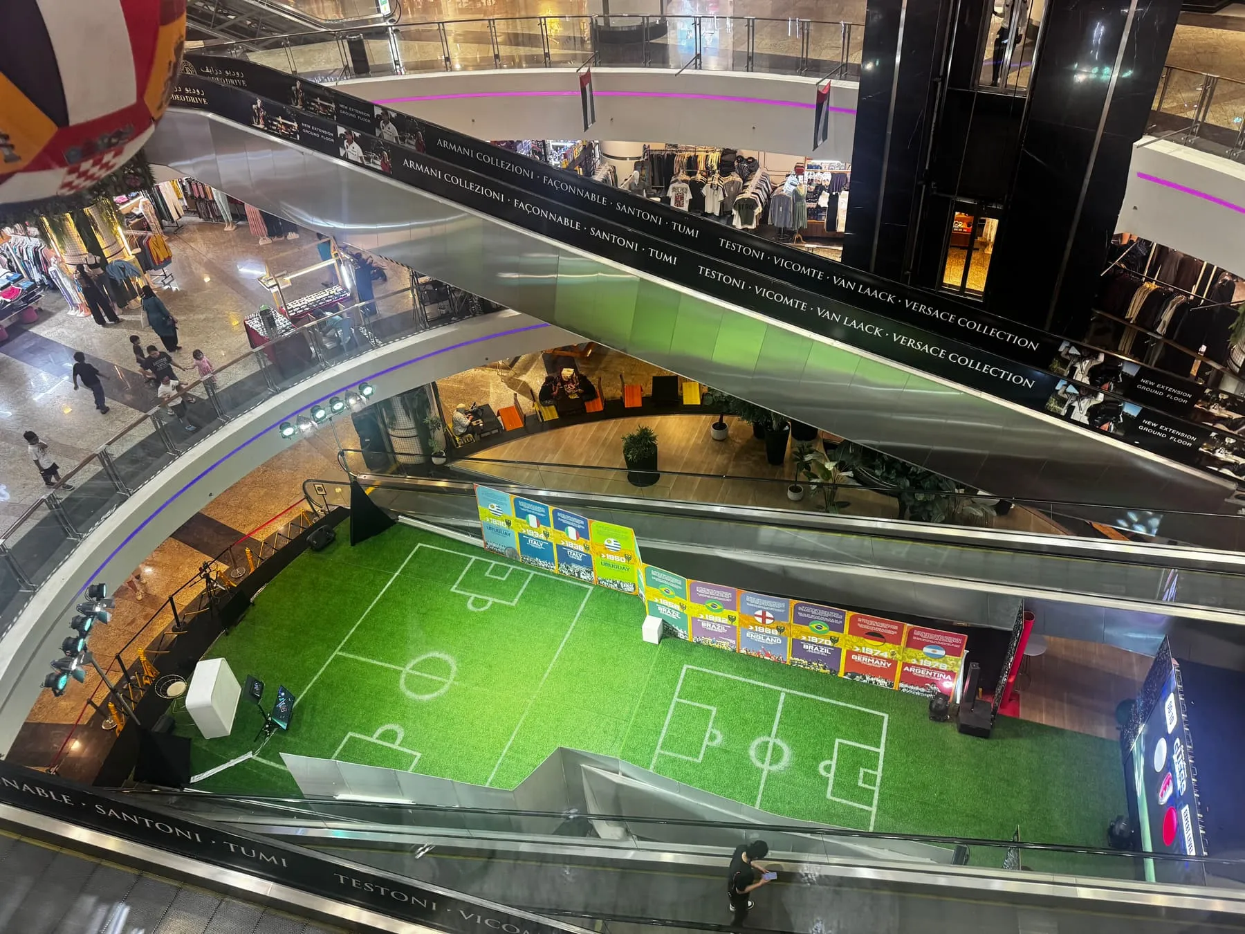 Blick von oben zwischen den Rolltreppen des Sahara Centre auf den WM-Kunstrasen mit Bannern vergangener Weltmeisterschaften