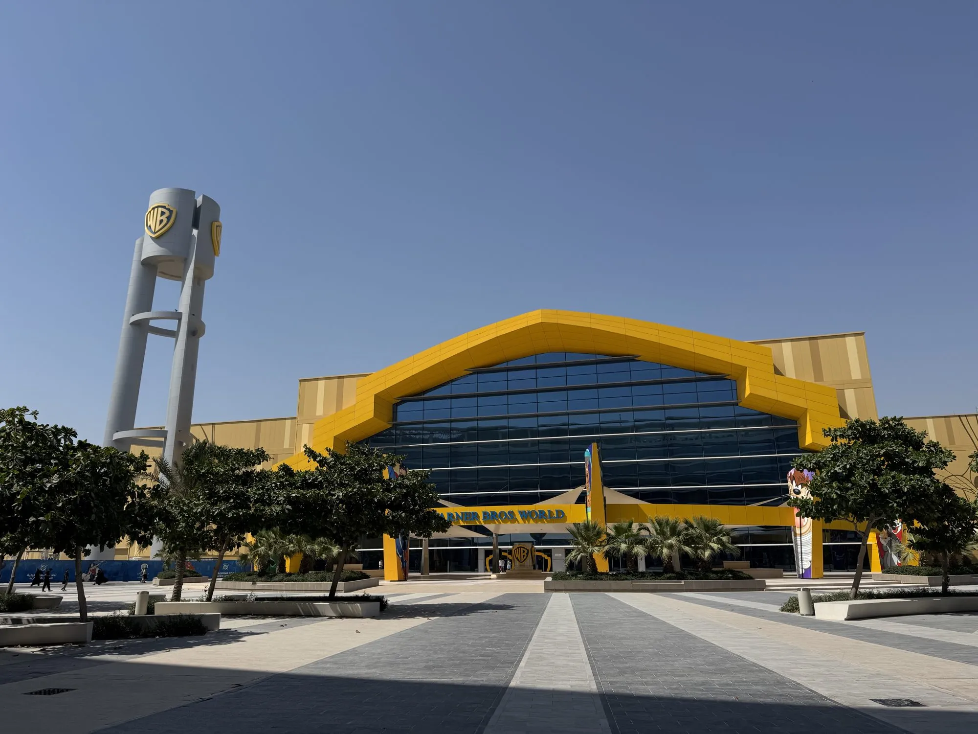 Gelbe Fassade von Warner Bros. World Abu Dhabi mit dem WB-Turm vor blauem Himmel