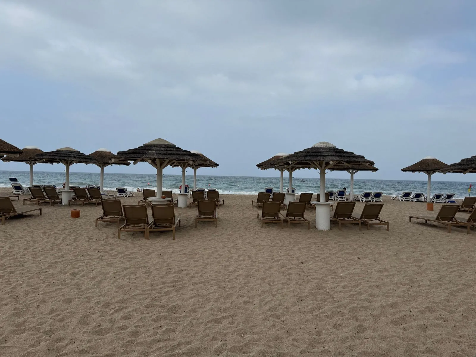 Strand des Fujairah Rotana Resorts in Al Aqah mit Strohschirmen, Sonnenliegen und ruhigem Meer