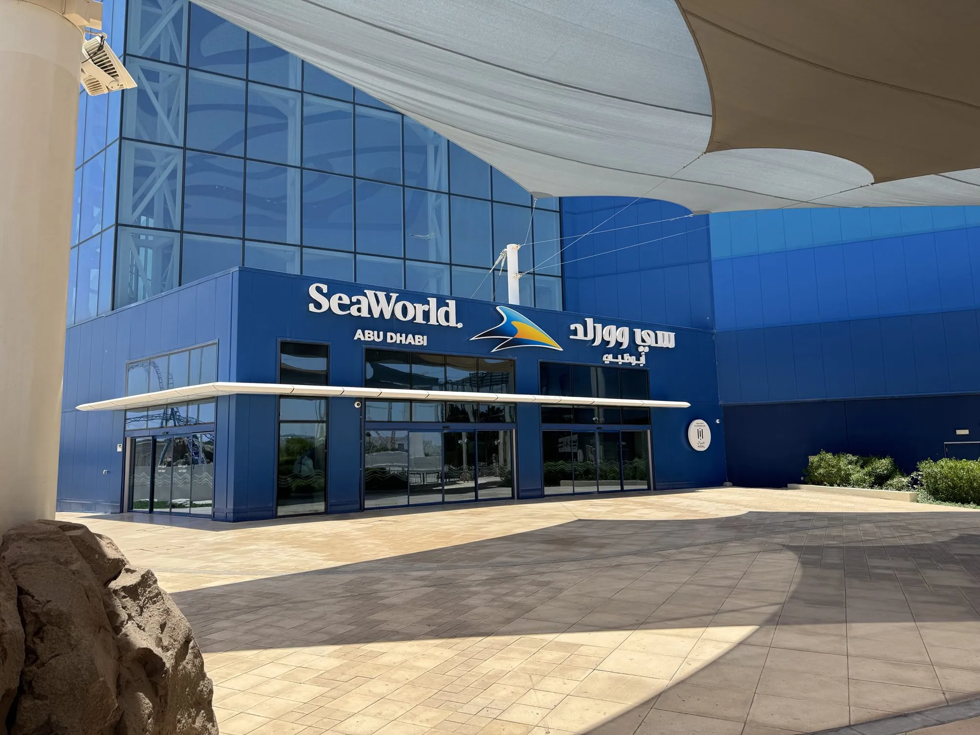 Blaue Fassade des SeaWorld Abu Dhabi mit Logo unter der geschwungenen Überdachung