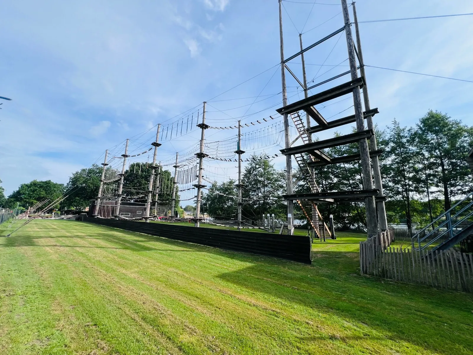 Kletterpark KlimKong mit hohen Holzpfahl-Türmen, Seilbrücken und Plattformen auf einer Wiese