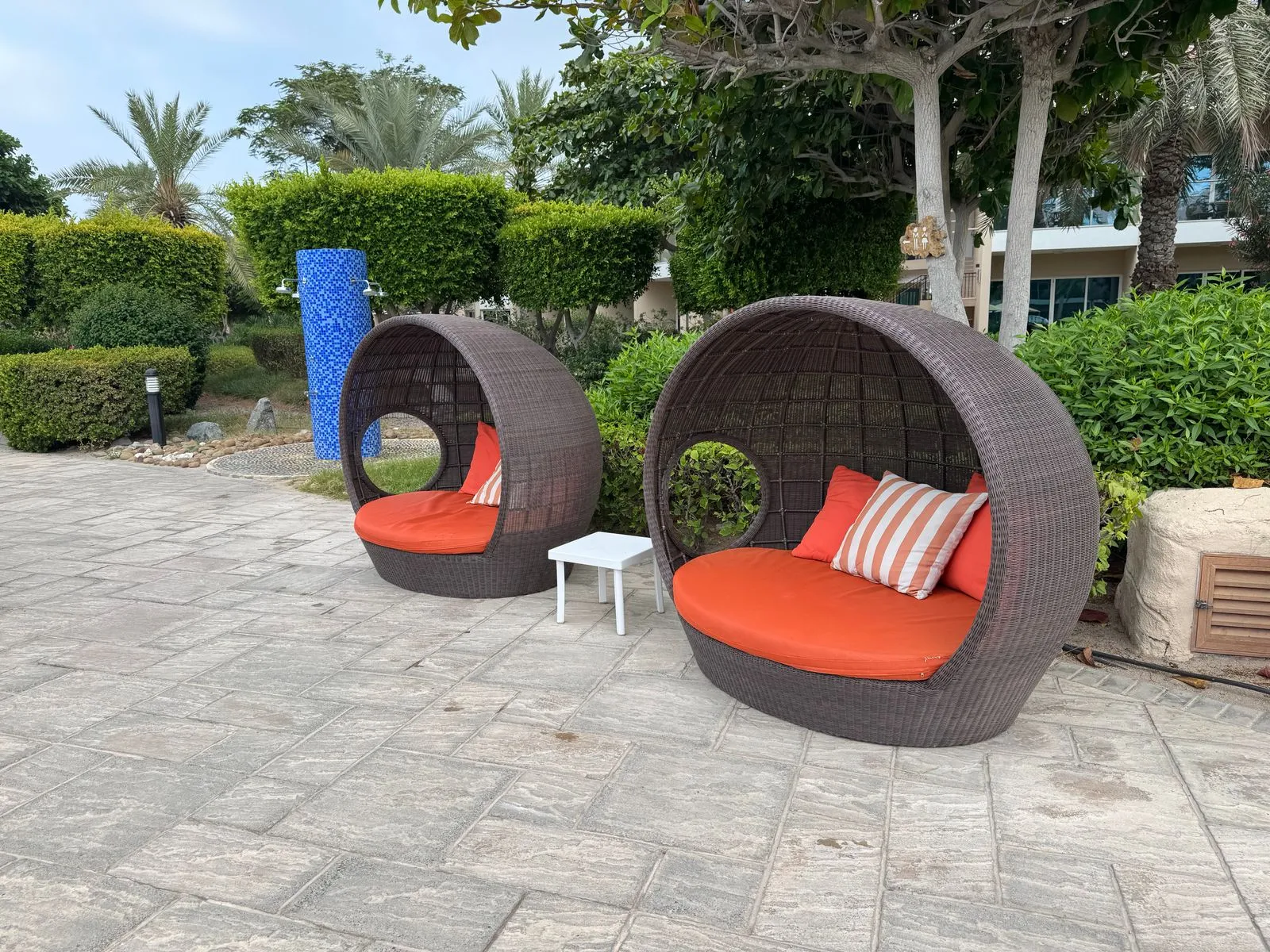 Runde Lounge-Muscheln mit orangefarbenen Polstern am Pool
